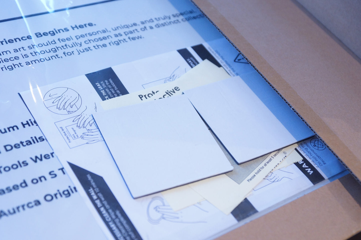 Inside view of Aurrca’s metal poster packaging featuring premium wall magnets, adhesive pads, and illustrated mounting instructions.