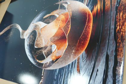 Close-up of glossy metal poster featuring abstract glass sphere artwork with warm lighting reflections