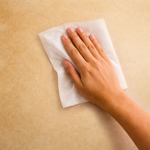 Hand cleaning wall with wipe before applying adhesive mount